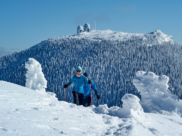 Schneeschuhwandern über den verschneiten Arber Schneeschuhwanderer durchschreiten eine verschneite Winterlandschaft mit Arbergipfel im Hintergrund